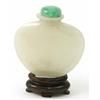 Image 1 : A pale green jade snuff bottle, of flattened vase shape, with stopper (2.25in.), on wood stand...