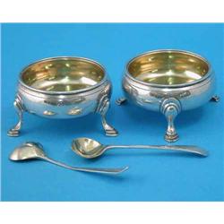 A pair of George III silver bun salts, on scroll feet, London 1772, and a pair of later spoons wi...