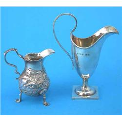 A George II silver cream jug, with scroll handle, decorated with engraved and repousse rococo scr...