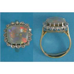 An 18ct gold ring, claw-set with a cushion shaped opal bordered by 16 round-cut diamonds...