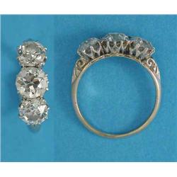 A 3-stone diamond ring, the old brilliant cut stones claw-set in white gold, carved shoulders, ce...