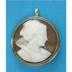 A gold framed circular shell cameo brooch/pendant, carved with a profile study of a lady wearing...