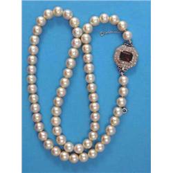 A single row necklace, of uniform cultured pearls, the hexagonal white gold clasp set with a rect...