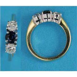 An 18ct gold and platinum 3-stone ring, claw-set with a round-cut central sapphire and flanked by...
