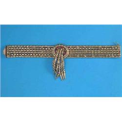 An 18k gold wide flexible bracelet, of fancy linking, the front with a tassel motif set 5 rubies,...