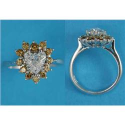An 18ct white gold diamond ring, claw-set with a heart shaped diamond bordered by 12 round-cut ye...