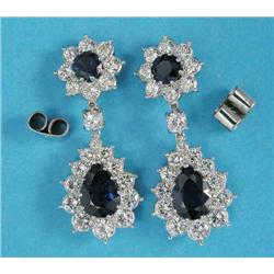 A pair of sapphire and diamond pendant earrings, each with a pear shaped sapphire bordered by 12...