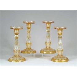 SET OF FOUR BOHEMIAN AMBER AND CLEAR CUT CANDLESTICKS.