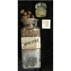 Large 10" x 3 1/4 Apothcary Jar with glass Stopper, some contents included.  Labeled "Myristica".  A