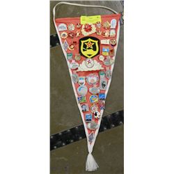 PENNANT COVERED IN RUSSIAN PINS AND CAP BADGES.