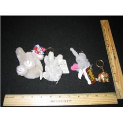 Four elephant key chains, three are plush guys with their certification cards. The other is a gold b