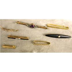 A GROUP OF SEVEN PINS