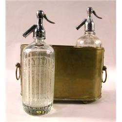 A PAIR OF MINERAL WATER SELTZER BOTTLES IN A BRASS SHEATH