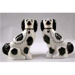 A PAIR OF BLACK AND IVORY STAFFORDSHIRE DOGS