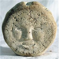 A carved weathered whalebone sculpture depicting two human faces by an unidentified Inuit artist.