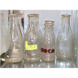 SHELF OF VINTAGE ROUND MILK BOTTLES.