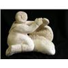 Image 1 : Un sujet inuit en os de baleine sculpté représentant un personnage assis près d’un masque.