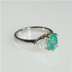 18k Yellow And White Gold Ring set with an oval cut emerald (approx. 1.38ct.) flanked by 2 trilliant