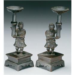 Pair of Bronze Candlesticks each with the figure of a boy on a waisted plinth holding aloft a knoppe