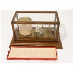 An early 20th century barograph, in walnut glazed case on bevelled base and feet, with box of charts