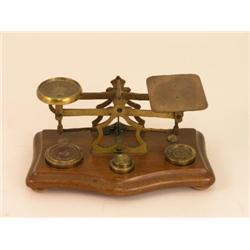 A set of brass table postal scales, on wooden base with weights inset, 8ins  