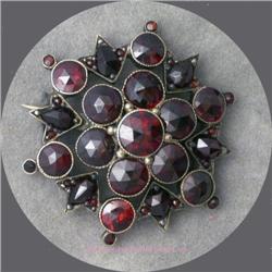 VINTAGE GARNET STONE BROOCH SET IN SNOWFLAKE PATTERN.