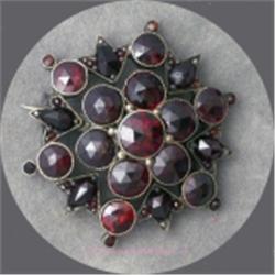 VINTAGE GARNET STONE BROOCH SET IN SNOWFLAKE PATTERN.