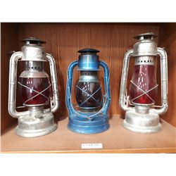 THREE RED GLASS OIL LANTERNS