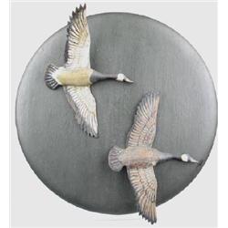 Two miniature flying Canada geese mounted on a bl