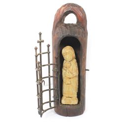 Early carved stone figure of St. Peter the Apostle inside a carved wooden niche with wrought iron ga