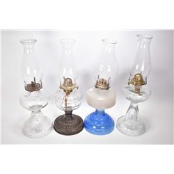 Four vintage oil lamps including three colourless including one with metal base and a milk glass wit