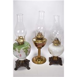 Two vintage oil lamps with glass painted fonts plus a brass oil lamp, all with clear chimneys