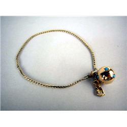 A 14K YELLOW GOLD CHARM BRACELET WITH A GLOBE CHARM With small turquoise stones and a gold hand char