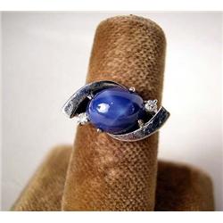 A 14K WHITE GOLD AND SYNTHETIC STAR SAPPHIRE RING With two circular full cut diamonds, total weight 