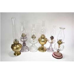 Six vintage oil lamps including brass Bradley & Hubbard with hurricane, metal lamp, four colourless 