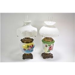 Two vintage banquet style oil lamps both with cast bases, hand painted floral detailing and milk gla