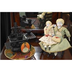 Two antique china head dolls including a 14" and a 10 1/2" on a cast and wooden rocking chair plus a