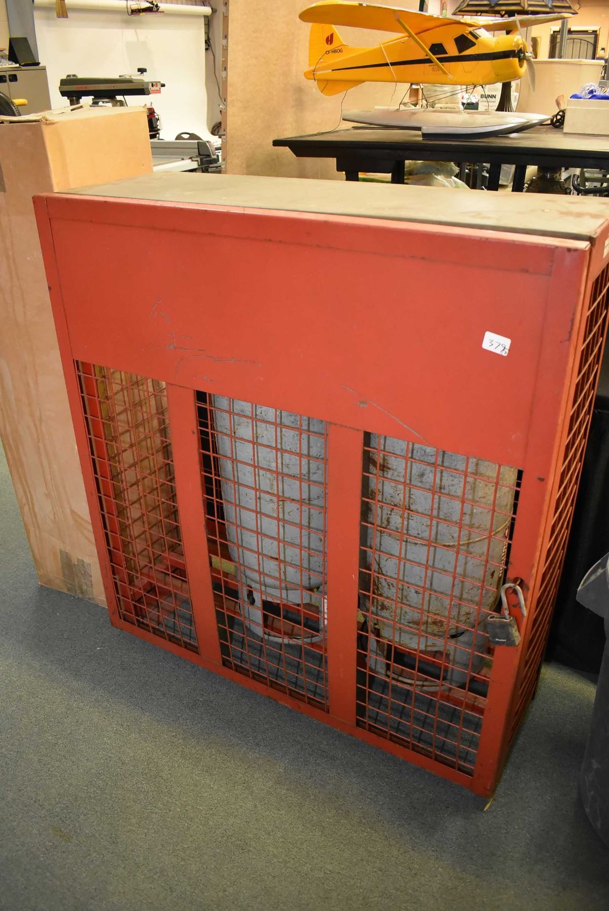 Lockable propane tank storage cage and two empty forklift propane bottles