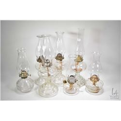 Seven colourless glass oil lamps with hurricanes including finger lamps etc.