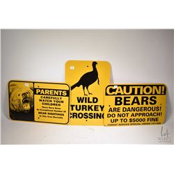 Three metal signs including two bear warning signs and a wild turkey crossing