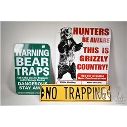 Three metal signs including two bear warning signs and a no trapping sign