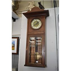 Antique wall hanging wood cased clock with visible pendulum behind six bevelled glass panels, not wo