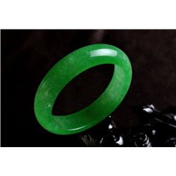 A NATURAL GREEN JADE BANGLE.