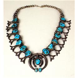 AN OLD NAVAJO HAND WROUGHT SILVER AND TURQUOISE SQUASH BLOSSOM NECKLACE