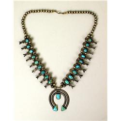 AN OLD NAVAJO HAND WROUGHT SILVER AND TURQUOISE SQUASH BLOSSOM NECKLACE