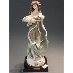 Guiseppe Armani cast resin figure of a woman wearing a flowing floral pattern dress and holding a ba