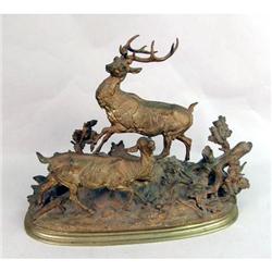 A GILDED WHITE-METAL FIGURAL SCULPTURE DEPICTING A MAJESTIC STAG AND HIS MATE IN A WOODLAND SETTING