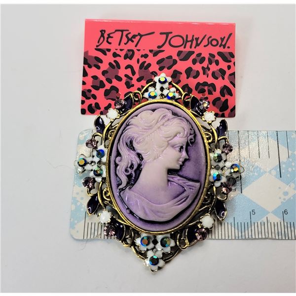 8)  BY DESIGNER BETSEY JOHN MAUVE CAMEO GOLD TONE BROOCH WITH WHITE ENAMEL AND CRYSTAL ACCENTS.