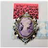 Image 1 : 8)  BY DESIGNER BETSEY JOHN MAUVE CAMEO GOLD TONE BROOCH WITH WHITE ENAMEL AND CRYSTAL ACCENTS.