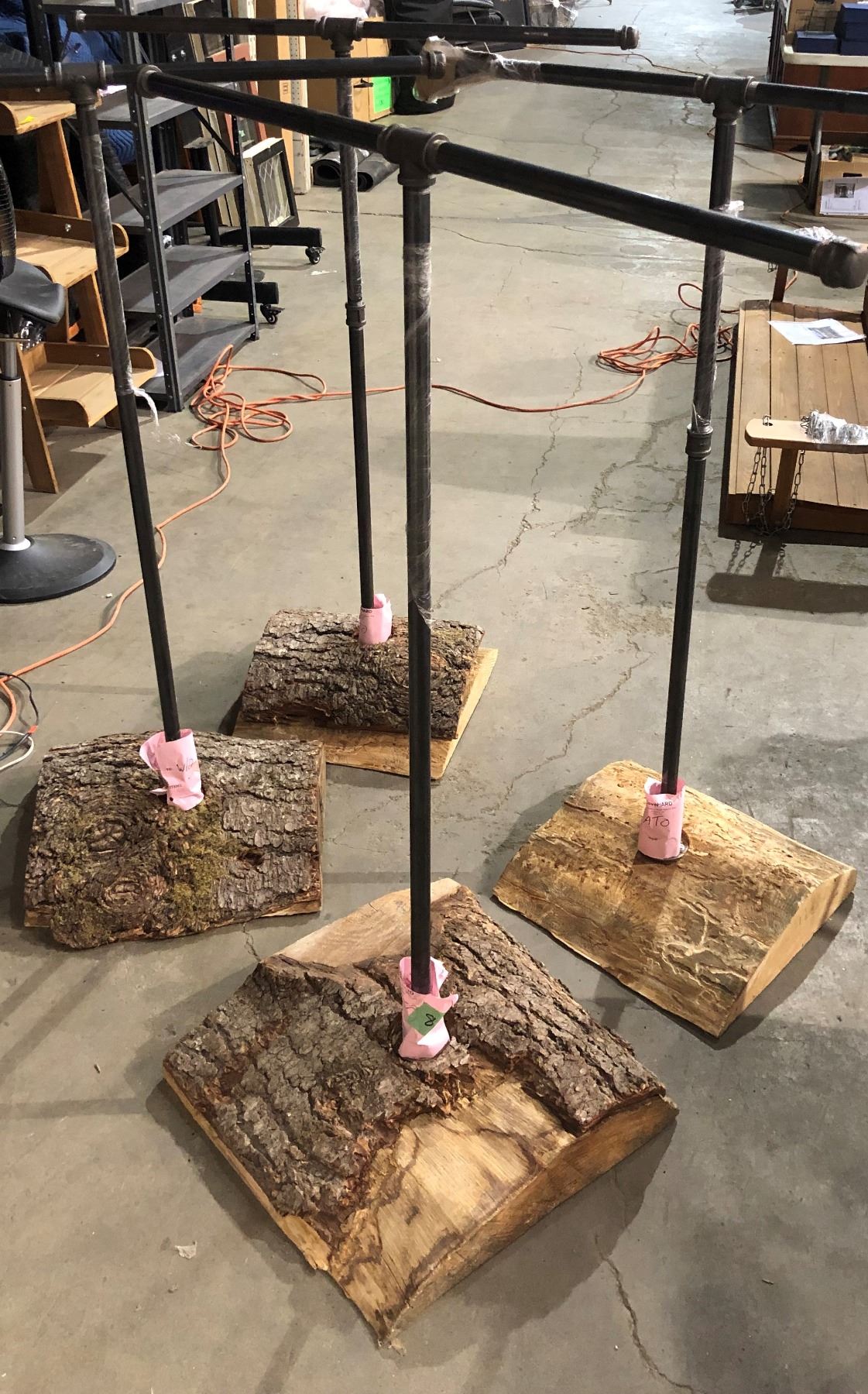 Group of 4 metal pipe clothing racks w/ wood stump bases from the love show